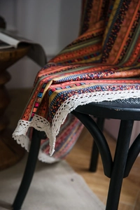 Detail of bohemian striped linen fabric with white lace trim draped on a black chair