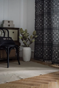 Detail of bohemian curtain featuring black geometric jacquard patterns and tassel edges