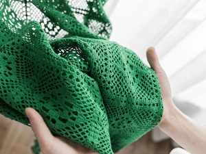 Detail of green crochet cotton curtain with vintage hollow patterns and lace edge texture