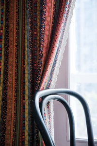Detail of bohemian striped cotton linen curtain with elegant white lace trim for home decor