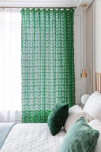 Detailed macro view of green crochet lace curtain with hollow geometric pattern and tassels