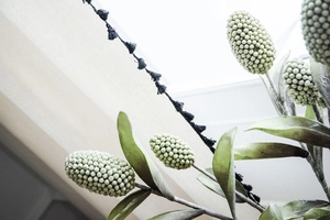 Detailed view of artificial Banksia plant with long green leaves and tassel trim detail