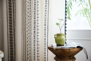 Detail of bohemian cotton linen curtain with black geometric print and stylish tassels