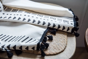 Close-up of cotton linen fabric with black geometric patterns and handmade tassels