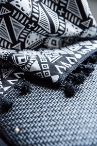 Close-up of geometric jacquard fabric with black tassels and bohemian weaving texture