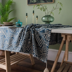 Blue and white geometric pattern table runner with tassels on a white wooden table