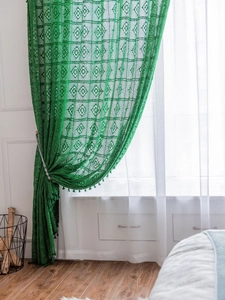 Detail of green crochet lace curtain with geometric patterns and fringe trim details
