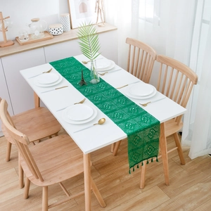 Close-up of green hollow lace table runner with geometric crochet patterns and tassels