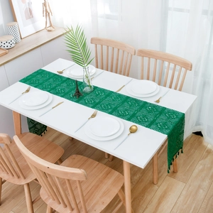 Detail view of green crochet lace table runner with intricate hollow patterns and tassels