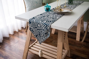 Detail of navy blue Nordic table runner with geometric triangle patterns and beige tassels
