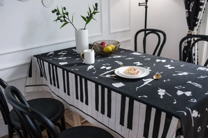 Detail of music-themed tablecloth featuring piano keys pattern and instrument silhouettes