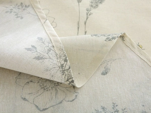 Macro detail of natural cotton linen tablecloth with delicate floral print and stitched edge