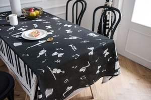 Detail of black tablecloth with white musical instrument prints and piano key border