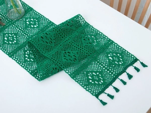Macro detail of emerald green crochet table runner with hollow floral pattern and tassels