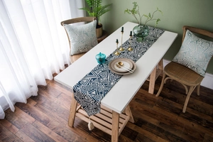Detail view of navy blue geometric triangle table runner with off-white tassel fringe