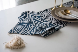 Detail of navy blue geometric jacquard table runner with decorative off-white tassels