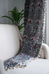 Detail of vintage floral cotton linen fabric with tassels draped on a sofa armrest
