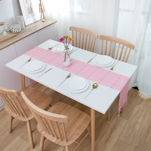 Close-up of pink lace table runner featuring hollow-out floral patterns and fringes