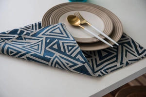 Detail of navy blue jacquard table runner with geometric triangles and ceramic tableware