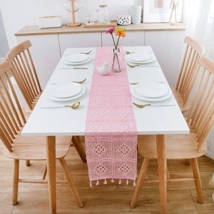 Pink crochet table runner with floral lace pattern and tassels for rustic dining decor