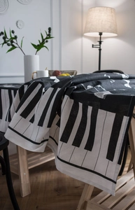 Detail view of piano key pattern tablecloth with musical notes and natural cotton texture