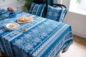 Detalle de mantel de lino azul con estampado de mandalas de encaje blanco y cojines