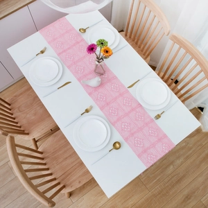 Detailed macro view of pink lace table runner with hollow crochet floral embroidery and tassels