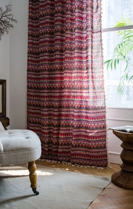 Detail of bohemian red printed curtain with cotton linen texture and decorative tassels