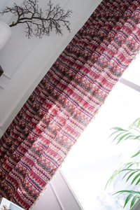 Detail of red Bohemian cotton linen curtain featuring ethnic geometric patterns and tassels