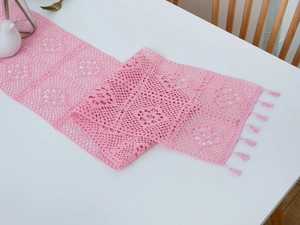 Detailed macro of pink crochet table runner with hollow floral pattern and cotton tassels