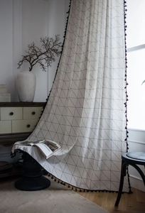 Detail view of cotton linen curtain with geometric triangle print and black tassel fringe