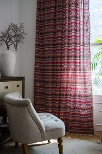 Close-up of bohemian red curtains with ethnic geometric patterns and beige fringe tassels