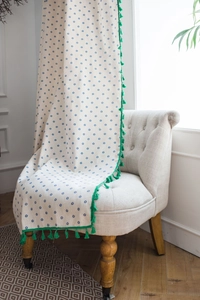 Dettaglio della tenda in cotone bianco con stampa margherite e bordo a nappe verdi