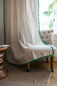 Dettaglio del tessuto in cotone e lino con stampa a margherite e nappe verde smeraldo