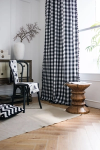 Detail of black and white plaid curtains with tassels and Nordic print table cloth