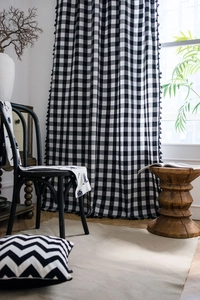 Detailed view of black and white gingham curtains with elegant black tassel fringe accents