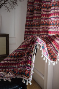 Detailed macro view of bohemian red curtains with geometric patterns and white tassels