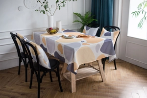 Detail of cobblestone print tablecloth and chair covers in yellow and gray geometric pattern