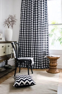 Close-up of black and white gingham curtains with elegant pom-pom tassels and linen texture
