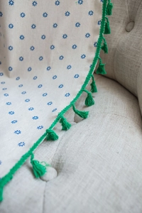Dettaglio in tessuto di lino beige con stampa a margherite blu e nappe decorative