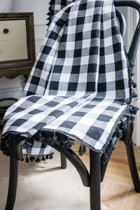 Detail of black and white buffalo plaid fabric with dense black fringe tassels