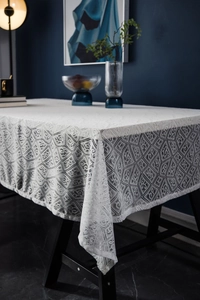 Close-up of elegant white lace tablecloth with geometric hollow patterns on dining table