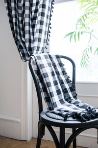 Detail view of cotton linen buffalo check curtain with elegant black tassel trim on the edge