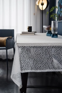 Close-up of white lace tablecloth with geometric rhombus pattern and hollowed textures