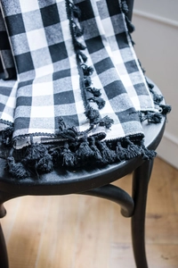 Detail view of black and white gingham curtain fabric with dense tassel fringe trim