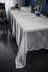 Close-up of modern white lace tablecloth with geometric hollow patterns and wavy edges