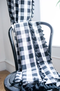 Detail of black and white buffalo check curtain with elegant decorative fringe balls