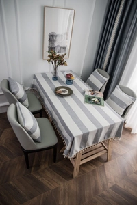 Detail of gray striped tablecloth with cream tassels and matching cushion set