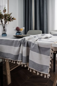 Close-up of gray striped tablecloth with decorative white tassels and woven texture