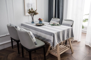 Close-up of gray striped linen tablecloth with white decorative tassels in Nordic style